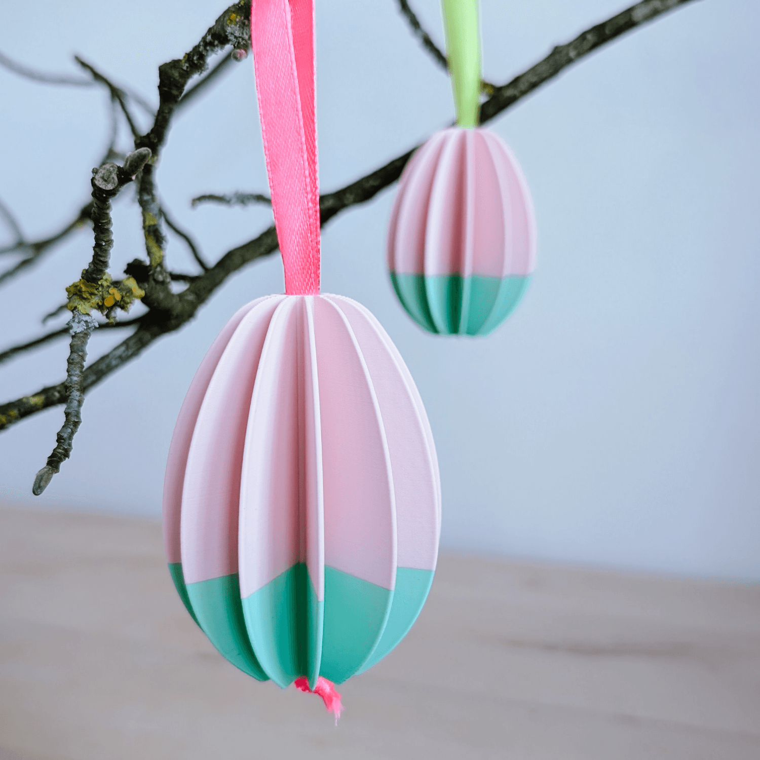 Hängende Ostereier in Rosa und Mint an einem Zweig
